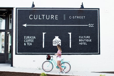 女人骑着青色自行车在街上看海报